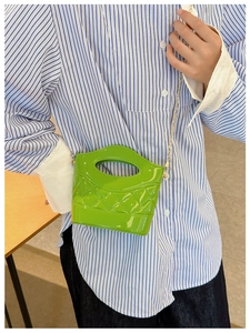 Dettaglio mini borsa a secchiello verde erba con finitura lucida e catena dorata