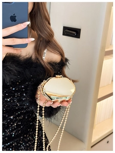 Mini gold octagonal metal bag with beaded chain shown as crossbody on shoulder