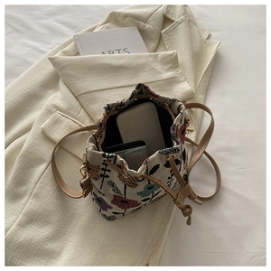Close-up of ethnic drawstring bucket bag interior with floral patterns and leather strap