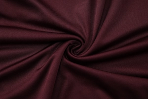 Gros plan sur le tissu rouge vin plissé montrant la texture douce et les détails