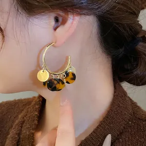 Vintage leopard print C-shaped hoop earrings with gold discs on a model with a sweater
