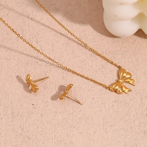 Detail view of 18K gold plated stainless steel bow pendant necklace and matching stud earrings