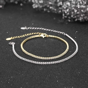 Close-up of gold and silver tennis bracelets with adjustable chains on a dark background
