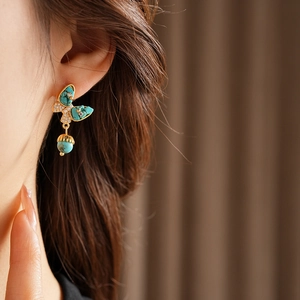 Gros plan de boucles d'oreilles papillon dorées avec incrustations de turquoise et perles