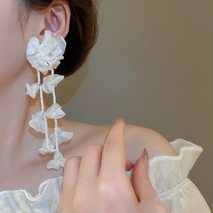 Detailed view of layered white chiffon flower tassel earrings on a model with bead accents