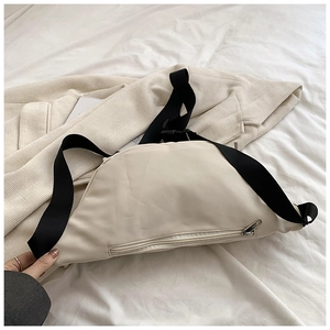 Detail of a cream crescent moon crossbody bag with adjustable black strap on corduroy fabric