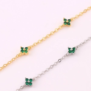 Macro view of gold and silver necklaces featuring green four-leaf clover crystal charms