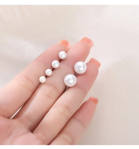 Comparison of various pearl earring sizes held in hand with soft beige background