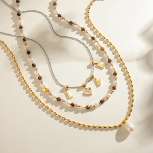 Stainless steel necklace set with freshwater pearls and heart-shaped pendant on white background