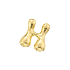 Macro detail of high polished golden metal letter H charm with smooth mirror finish