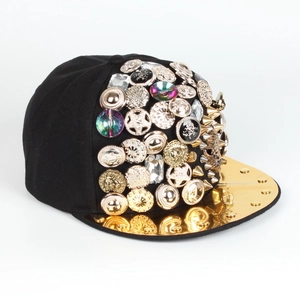 Dettaglio cappello snapback con visiera in metallo dorato e borchie punk decorative