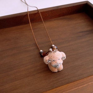 Close-up of plush puppy pendant with snowflake charms and beads on a wooden tray