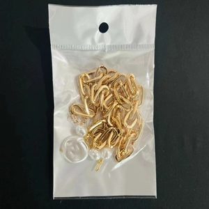 Detail of gold chain link necklace with white pearl charm in clear packaging