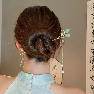 Détail d'un pic à cheveux à pompons en perles avec bourgeons de jade vert dans un chignon