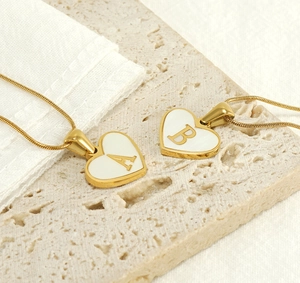 Detail of 18K gold-plated heart pendant with white shell inlay and letter engraving
