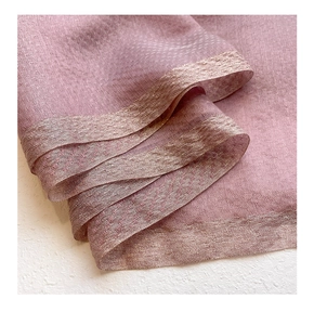 Detailed texture of pink silk wool scarf with subtle jacquard pattern and gold stitching