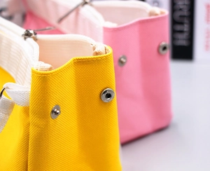 Makroaufnahme von Silber-Druckknöpfen und feinen Nähten auf der Tasche aus dichtem Canvas