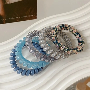 Detail showing set of six colorful spiral hair ties with floral and checkered patterns