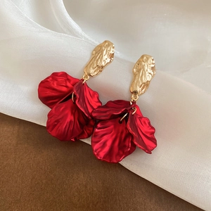 Detail of red acrylic flower petal earrings with golden hammer texture stud and tassels