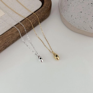 Macro detail of fluid waterdrop pendant in gold and silver finish with black gemstone