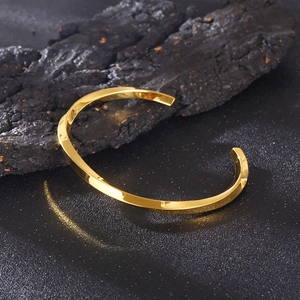 Classic golden Mobius twisted cuff bracelet in stainless steel on dark rock
