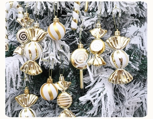 Detail of gold and white candy-shaped Christmas ornaments hanging on a snowy tree branch