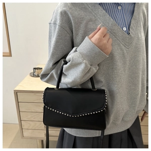 Detail of black PU leather handbag with silver rivets and detachable shoulder strap