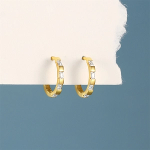 Detail of gold drop hoop earrings featuring rectangular white zircon stone settings