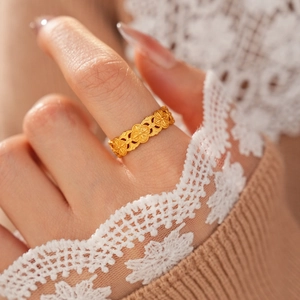 Gros plan d'une bague florale ajourée en plaqué or vintage sur un doigt gracieux