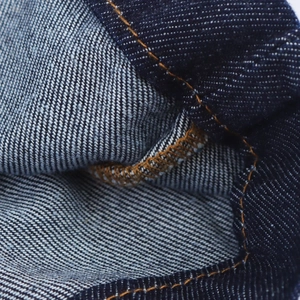 Vue macro du denim bleu foncé avec des coutures renforcées jaunes et texture