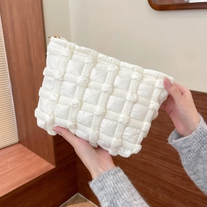 Close-up of white bubble quilted canvas makeup bag with golden zipper and soft texture