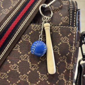 Detailed view of mini baseball keychain with blue leather ball and wood bat on a bag