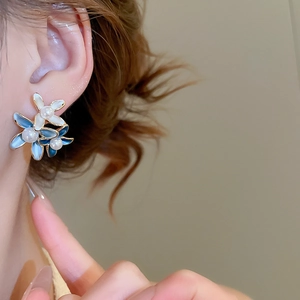 Close-up of 18K gold plated flower earring with blue petals and center pearl detail