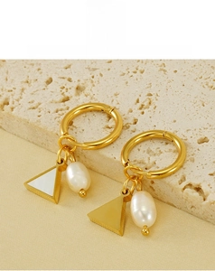 Detailed macro of gold-plated geometric earrings with natural pearl and triangle charms