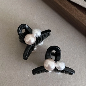 Mini pinces à cheveux noires avec perles blanches et roses sur fond texturé