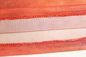 Macro shot of orange mesh fabric texture and stitching detail on women's dress