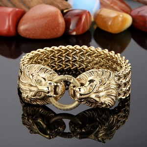 Detail of gold lion head link bracelet with thick braided chain on black reflective surface