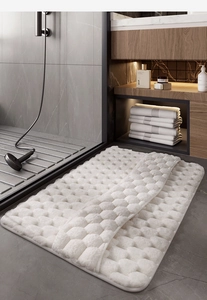 White memory foam bathroom mat with 3D waffle texture on dark grey tile floor