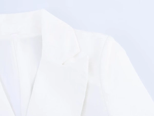 Close-up of white blazer notched lapel showing premium fabric texture and clean stitching