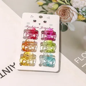 Detail view of 6 colorful mini bow hair claws on a cat-themed display card with springs