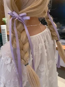 Détail du haut en dentelle brodée de fleurs blanches et pince à cheveux en ruban