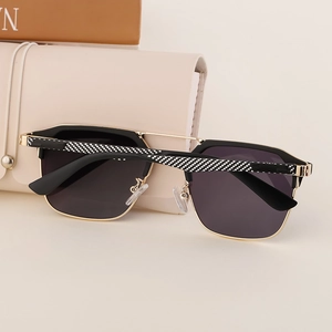 Detail of polygonal sunglasses with gold metal bridge and checkerboard textured temples