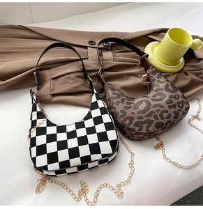 Detail of houndstooth and leopard print crescent bags with gold chain straps on fabric