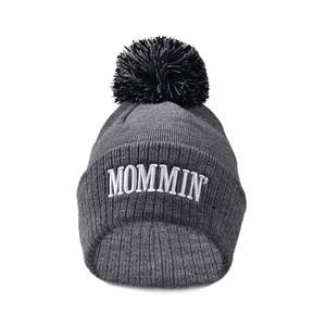 Close-up of MOMMIN embroidery and dark grey knitted texture with black fluffy pompom