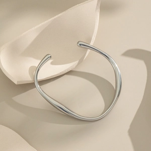 Detailed view of silver minimalist irregular C-shaped open bangle with smooth finish