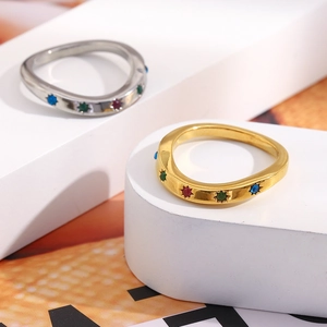 Macro detail of wave-shaped 18K gold ring with colorful gemstones and star engraving