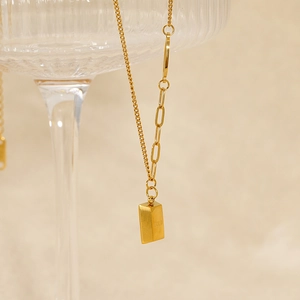 Detailed close-up of gold bar pendant with unique paperclip and O-chain design