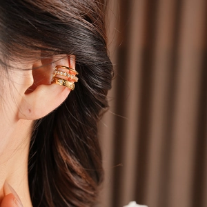 Dettaglio del ear cuff a tre strati placcato in oro con brillanti pietre di zirconite
