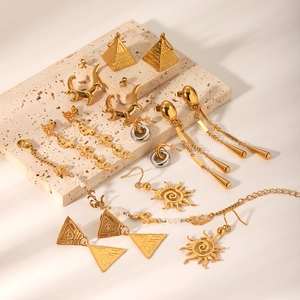 Collection of golden geometric earrings and jewelry sets on minimalist marble blocks
