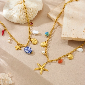 Detail of gold ocean-themed necklaces with starfish, shell, pearl, and coral charms